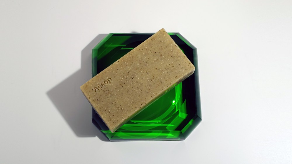 tan colored bar of soap with bits of exfoliant inside it and a minimalist white label