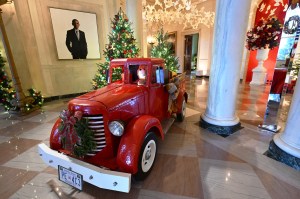 A vintage red truck can be seen near a portrait of former US President Barrack Obama in the Grand Foyer near the Cross Hall during the 2024 White House Holiday media preview in Washington, DC, on December 2, 2024.