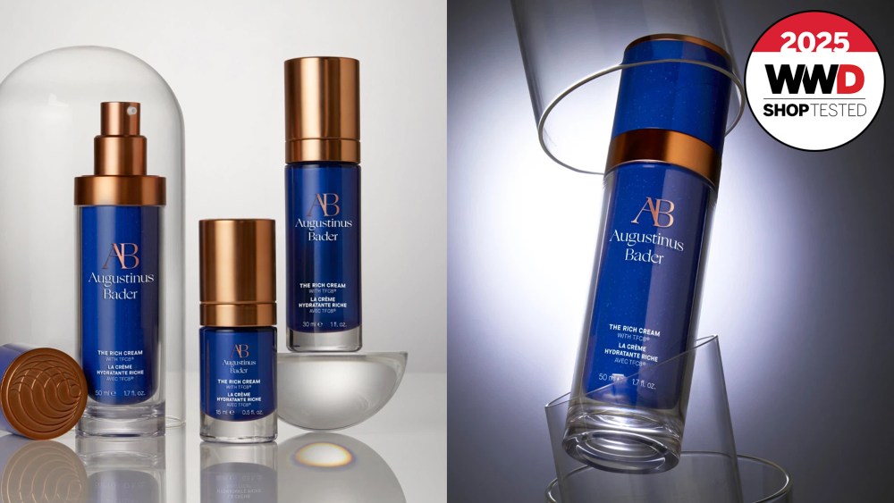 three navy and gold bottles of face cream placed on glass, set on a gray background