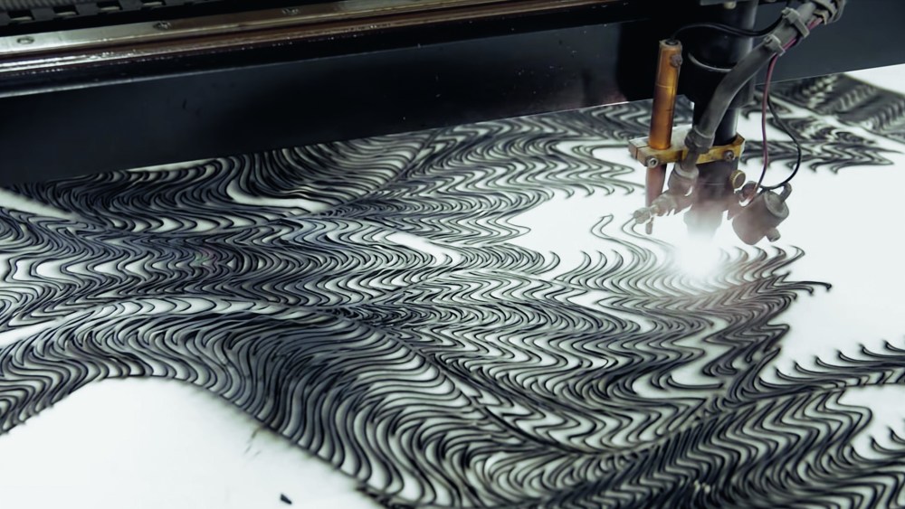 Black leather being laser cut in parametric wave patterns for a spheroid silhouette envisioned by Iris Van Herpen.