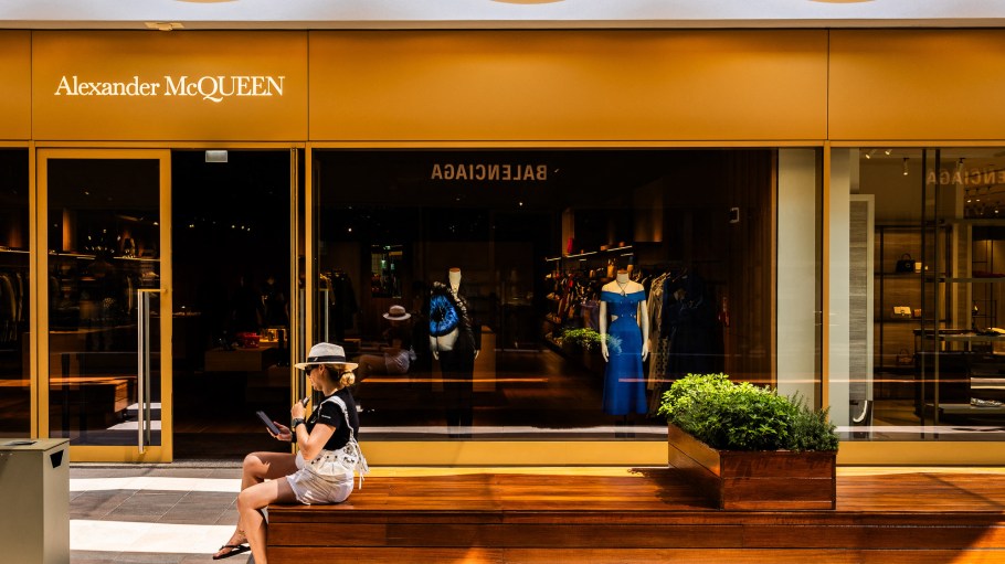 Woman on her telephone sitting in front of the Alexander McQueen boutique in The Mall Outlet on the outskirts of the town of Sanremo in Liguria, eastern Italy, July 31, 2024. (Photo by Jc Milhet / Hans Lucas / Hans Lucas via AFP) (Photo by JC MILHET/Hans Lucas/AFP via Getty Images)