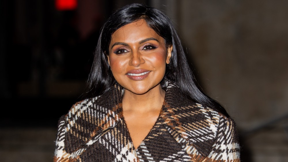 Mindy Kaling wears brown checkered jacket, skirt, tights, black bag with logo outside Patou during the Fall Winter 2025/2026 as part of  Paris Fashion Week on January 26, 2025 in Paris, France.