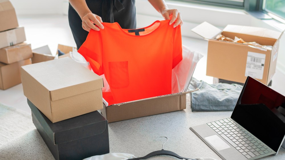 Online store selling clothes on website working on laptop ecommerce business from home. Woman packing new clothing fashion purchase in shipping packages for delivery. Panoramic banner.