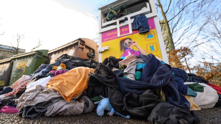 Used clothes lie in front of a collection container for old clothes in Leipzig.