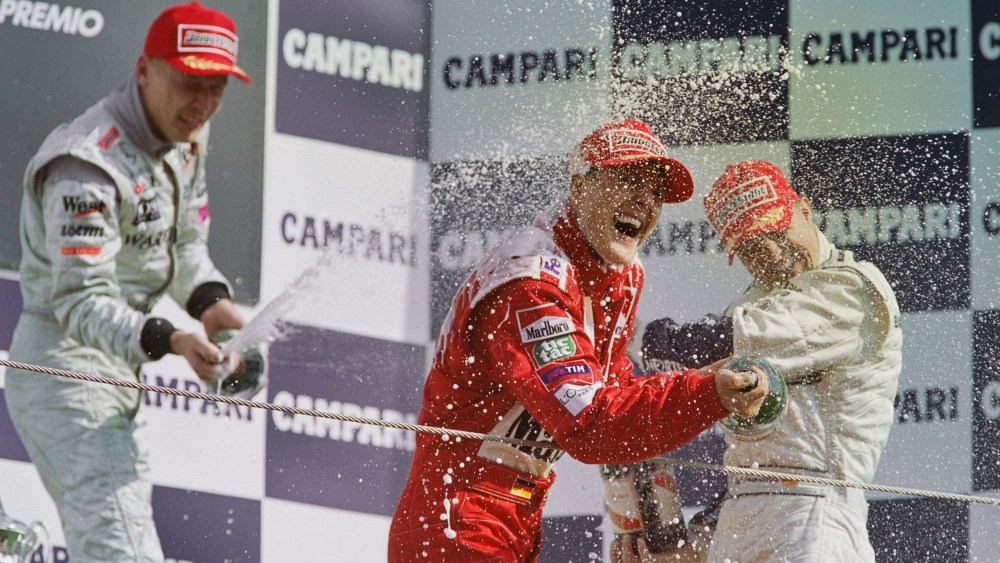Michael Schumacher from Germany, driver of the #3 Scuderia Ferrari Marlboro Ferrari F1-2000 Ferrari V10 sprays Mumm Cordon Rouge Champagne to celebrate winning the Formula One Italian Grand Prix with second placed Mika Häkkinen and his brother Ralf Schumacher in third place on 10th September 2000 at the Autodromo Nazionale Monza near Monza, Italy.  (Photo by Mark Thompson/Getty Images)