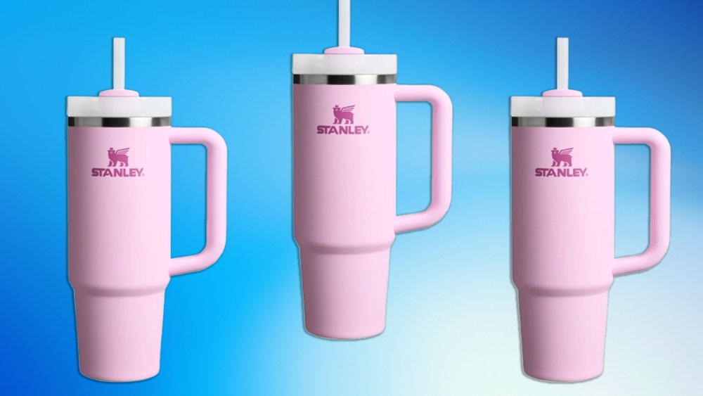 three stanley tumblers in a pink color over a blue gradient background