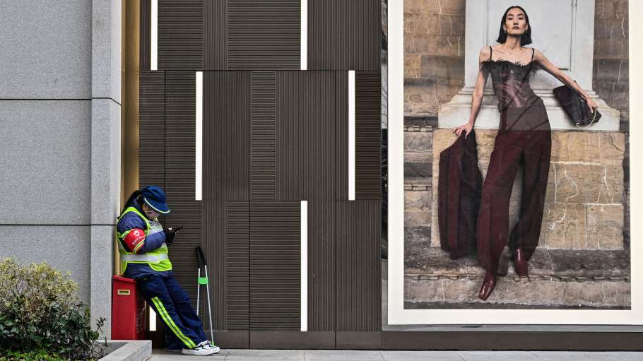 A worker stands next to a shopping mall in Shanghai.