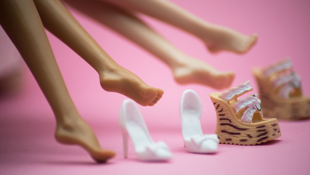Closeup of feet of mannequin dolls with shoes on pink background - Fashion victims concept