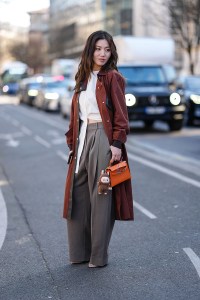 PARIS, FRANCE - MARCH 08: Cristine Sun wears burgundy bordeaux trench coat, white shirt, light gray high waisted trouser pants, shiny dark orange Hermès Kelly leather bag, dark brown Labubu charm, outside Hermès, during the Paris Fashion week Women's Fall/Winter 2025-2026 on March 8, 2025 in Paris, France. (Photo by Edward Berthelot/Getty Images)