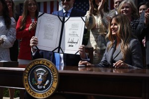 WASHINGTON, DC - MAY 19: U.S. President Donald Trump, seated next to first lady Melania Trump and joined by lawmakers and victims of AI deepfakes and revenge porn, holds a copy of the TAKE IT DOWN Act during a signing ceremony in the Rose Garden of the White House on May 19, 2025 in Washington, DC. The first lady made the Tools to Address Known Exploitation by Immobilizing Technological Deepfakes on Websites and Networks (TAKE IT DOWN) Act a priority, traveling to Capitol Hill to lobby lawmakers and show her support for the legislation, which addresses non-consensual intimate imagery, or "revenge porn," and artificial intelligence deepfakes posted online and to social media. (Photo by Chip Somodevilla/Getty Images)