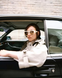 McQueen cotton gabardine trenchcoat and piqué polo shirt; Tommy Hilfiger crinkle silk-blend shirt; Valentino sunglasses; Zimmermann necklace with 12-karat gold brass detailing, natural Tiger’s Eye, Green Quartz Lapiz, Aquamarine and Freshwater Pearl stones.A