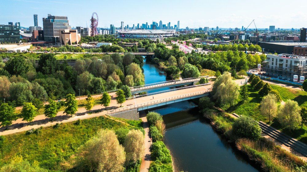 Aerial view, taken by drone, depicting the modern architecture of Stratford in East London. In the foreground is Stratford wetlands on the River Lea, while the skyline is dominated by Queen Elizabeth Olympic Park and London Stadium, home of West Ham United FC. The high rise towers of the Isle of Dogs, including Canary Wharf, are visible on the horizon.