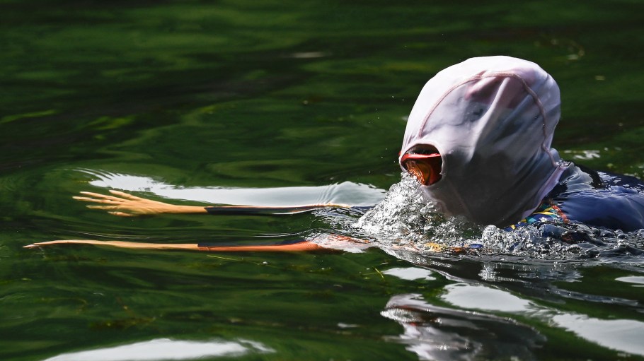 A person wearing a sun protection mask swims in a river in Beijing on June 25, 2025.