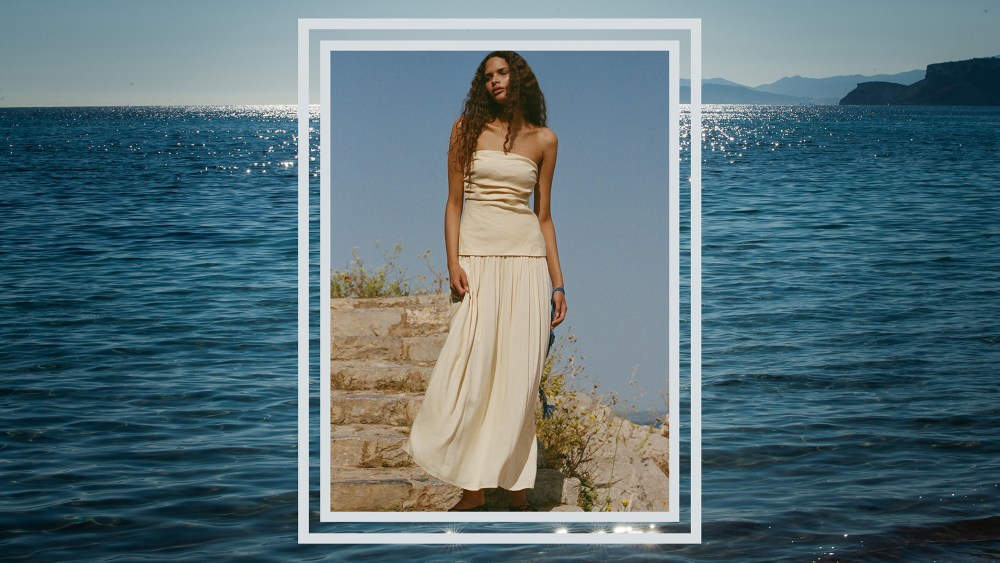 woman standing on coastal cliff side in Faithfull the Brand Hedy Dress with tropical water background
