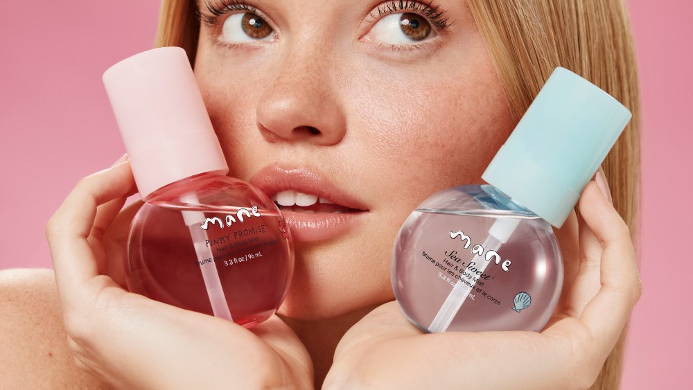 Model holding two Mane hair and body mists