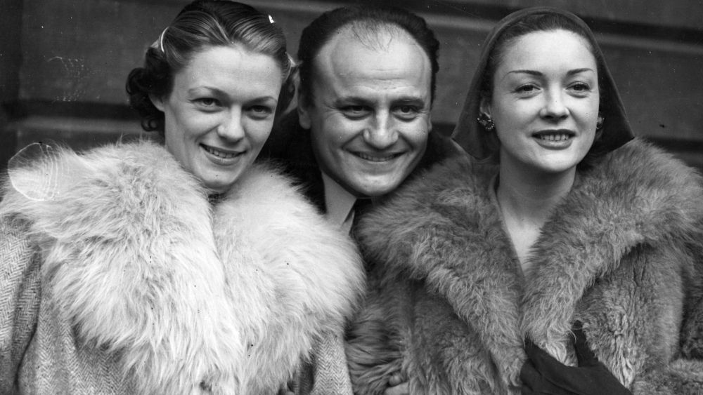 Pierre Balmain poses with models Suzette, left, and Praline, right, in Balmain furs at Victoria in London on Feb. 12, 1951.
