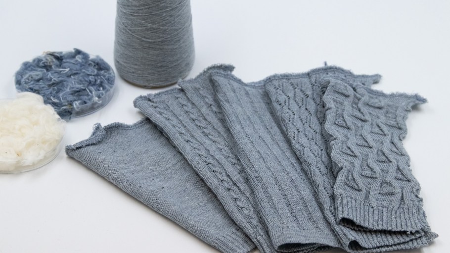 Knitted fabrics using yarn made of mechanically opened cotton fibers from post-consumer denim.