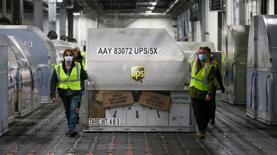 UPS employees move one of two shipping containers containing the first shipments of the Pfizer and BioNTech COVID-19 vaccine  inside a sorting facility at UPS Worldport on December 13, 2020 in Louisville, Kentucky.