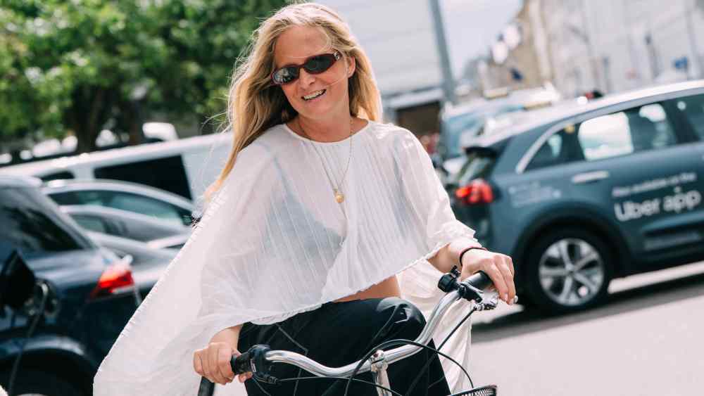 Female on bicycle wearing white sheer pleated shirt and sunglasses at Copenhagen Spring 2026 Fashion Week