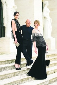 Giorgio Armani flanked by models in his designs.