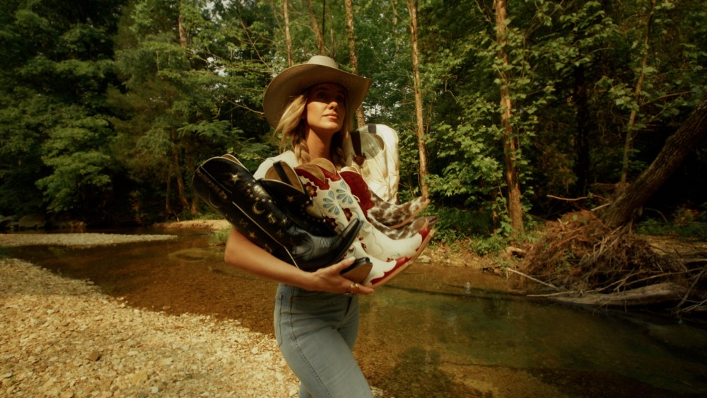 Lainey Wilson holding boots from her brand Golden West.