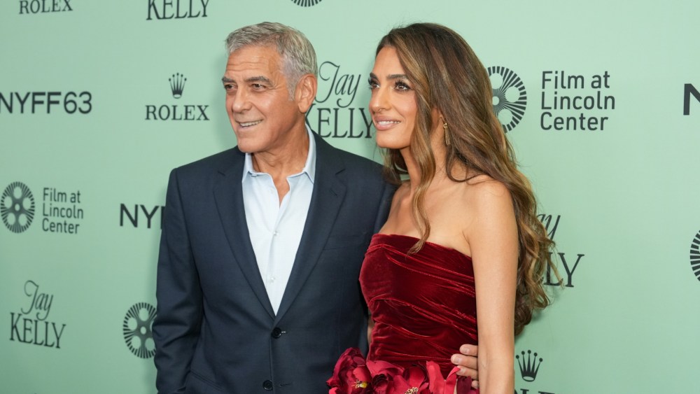 George Clooney poses alongside wife Amal Clooney, wearing a red floral dress from Oscar de la Renta's fall 2025 ready-to-wear collection, for the New York Film Festival premiere of the movie 'Jay Kelly' on Sept. 29 in New York City.