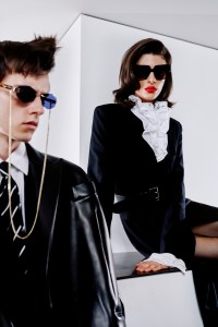 Brunson: Marc Jacobs rimless shape with metal frame and temples in acetate and metal chain sunglasses; Khaite leather jacket over Emporio Armani wool jacket; Gucci cotton shirt; Ralph Lauren Purple Label pants; Ralph Lauren Purple Label tie; Scarosso shoes.Erika: Kendra Scott acetate sunglasses; Ralph Lauren Collection wool dress, cotton top and belt; Commando tights; Nina Ricci platform heels.