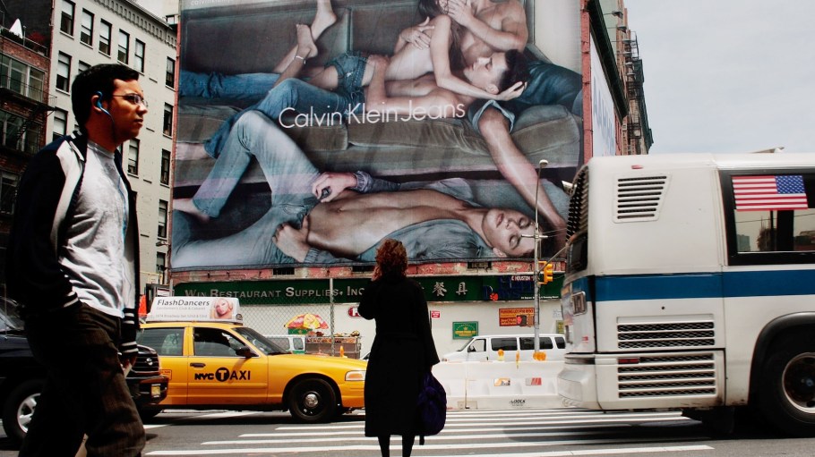 Pedestrians stand on a sidewalk near a Calvin Klein billboard on the side of a building June 17, 2009 in the SoHo neighborhood of New York City.