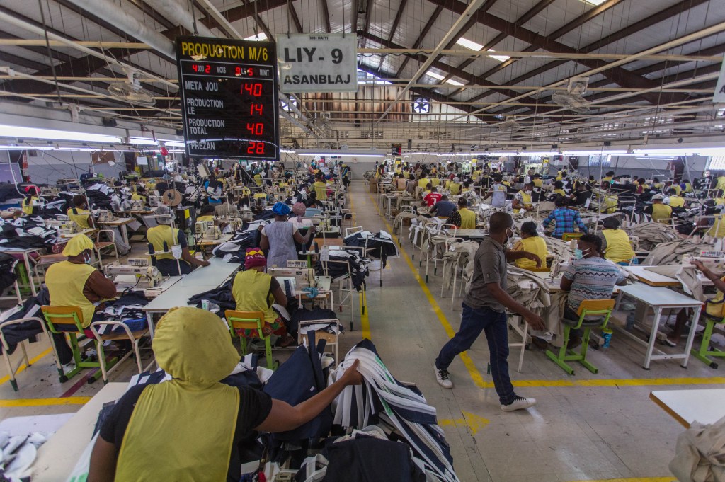 People wearing masks work at the MBI factory at the industrial park Sonapi in Port-au-Prince on April 21, 2020. A month after the country's closure due to a state of health emergency, the Prime Minister of Haiti Joseph Jouthe advocated for the reopening of factories in the textile sector on April 20, reopening which is undertaken with precautions, without eliminating all the risks for the workers. (Photo by Pierre Michel Jean / AFP)