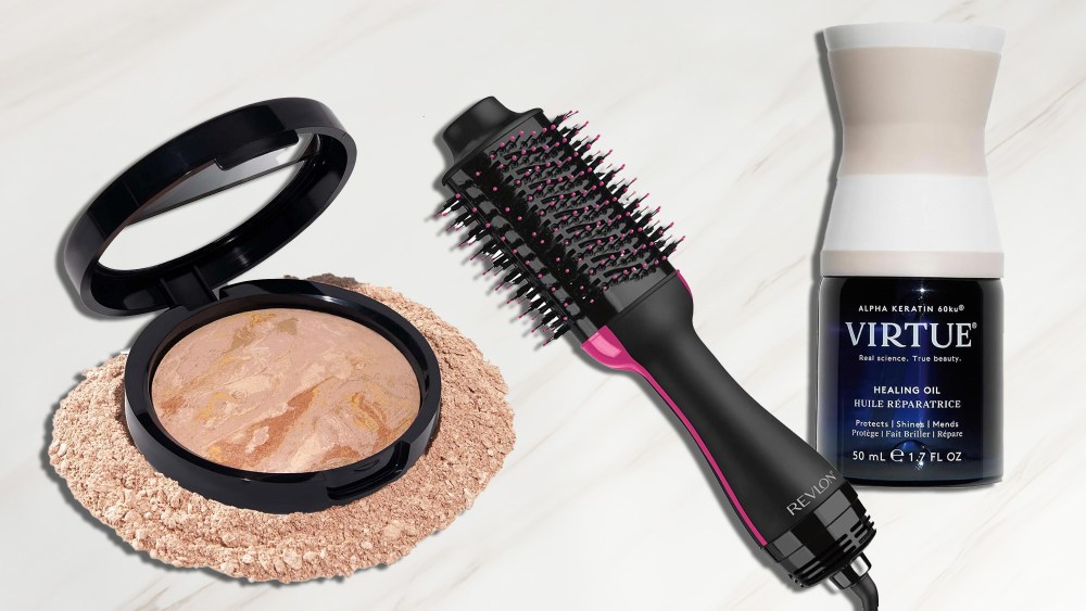 a foundation, hair styler tool, and healing oil from virtue over a white marble background