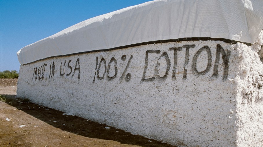A cotton module in a turnrow next to a harvested field with the message "made in USA 100% cotton."