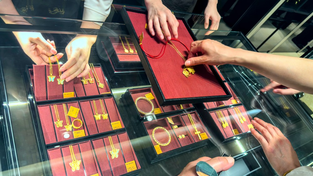 Employees show gold necklaces to customers at a Laopu Gold jewelry shop in Shanghai, China.