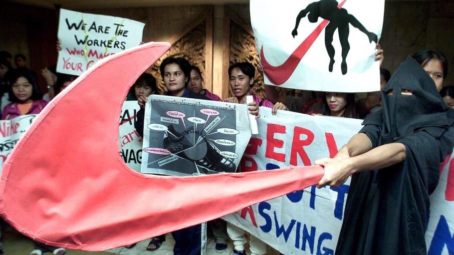 Thai Nike workers show a giant Nike logo during a protest after US golfer Tiger Woods received an honorary doctorate in sports science from a Thai University in Bangkok, 14 November 2000. The workers protesting were part of a group of 1016 who were still waiting  to be compensated after being laid off by Nike in September.