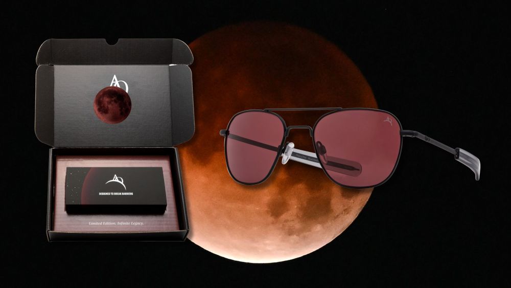 new american optical blood moon aviator sunglasses shown in their box and alone, overlaid on an image of the 2026 lunar eclipse