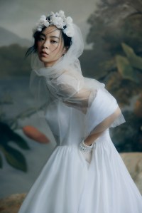 Honor taffeta cape and organza gown with glass embroidered neckline, cellophane hem and ribbon accents; Jennifer Behr tulle veil with silk organza flowers; stylist’s own gloves; Lele Sadoughi pearl bracelet.