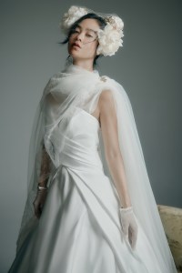 Mark Ingram Bride silk faille Saylor gown; Watters chiffon cape; Monvieve silk floral headband and organza veil (draped over the shoulder); stylist’s own gloves; Harwell Godfrey 18-karat yellow gold We Are Seeds Poppy Brooch; 
Miraki emerald tennis bracelet.