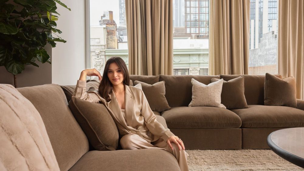 hailee steinfeld sitting on a brown sofa while wearing a robe; ashley luxe furniture line luxury