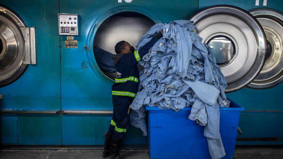 MASERU, LESOTHO - JULY 3: A garment factory worker moves denim products from an industrial dryer on July 3, 2025 in Ha Thetsane Industrial Area in Maseru, Lesotho. Lesotho garment manufacturer Presitex makes denim and exports exclusively to the South African jeans market. It is the largest garment factory in Lesotho, employing over 2000 workers. (Photo by Per-Anders Pettersson/Getty Images)